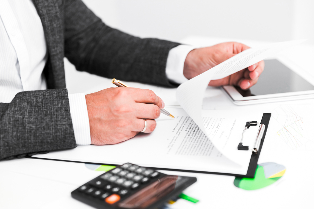 Person signing documents with calculator