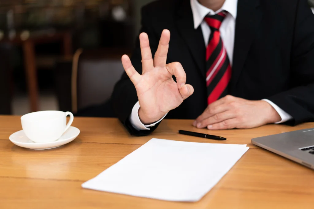 Businessman making okay gesture at desk